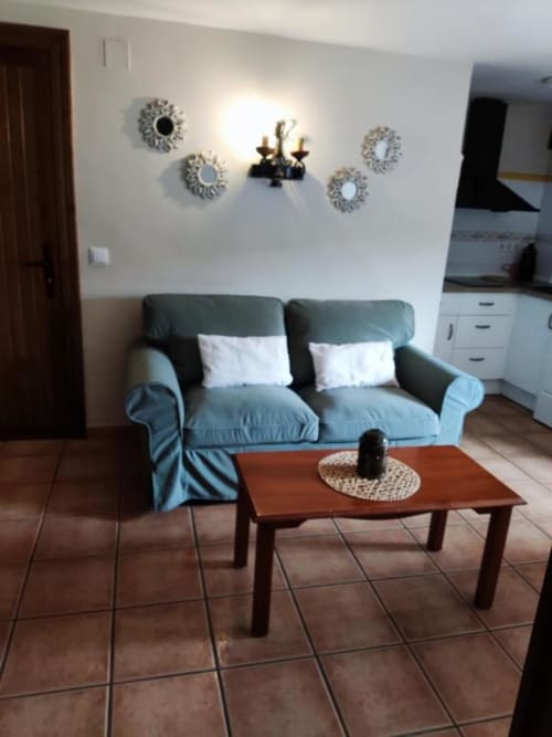 Sofá azul con cojines blancos y mesa de centro de madera en la sala del estudio Casa Lahuerta, Bronchales