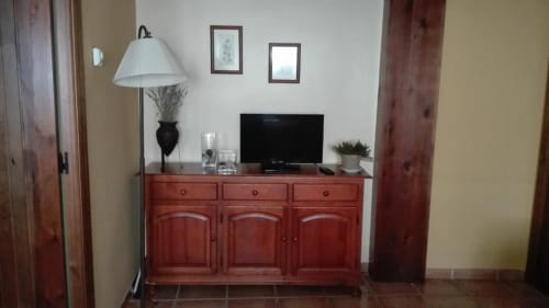 Armario de madera roja con televisor y lámpara de pie negra en el estudio Casa Lahuerta, Bronchales