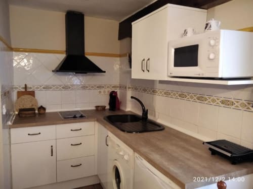 Cocina moderna del apartaestudio Casa Lahuerta en Casas rurales El abuelo, Bronchales, con muebles blancos y estufa negra
