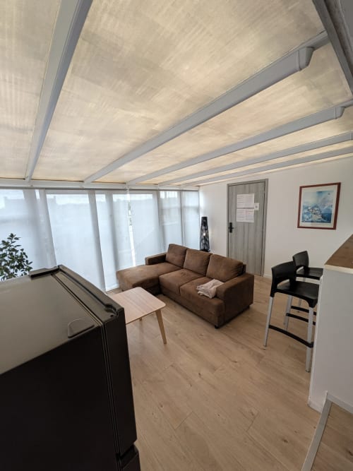 Salon moderne de la Résidence des dunes avec canapé marron, parquets et baies vitrées rétractables au plafond