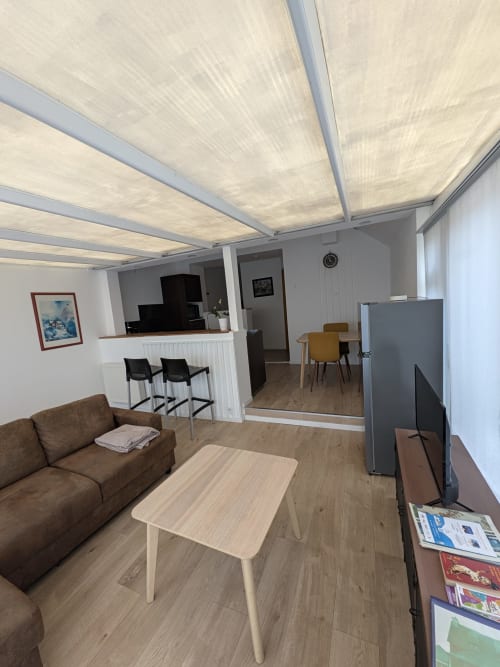 Séjour moderne à la Résidence des dunes, Landéda avec plafond rétractable, canapé marron, coin repas et cuisine