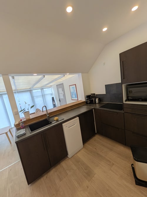Cuisine moderne de la Résidence des dunes avec mobilier sombre, électroménagers inox et baie vitrée panoramique