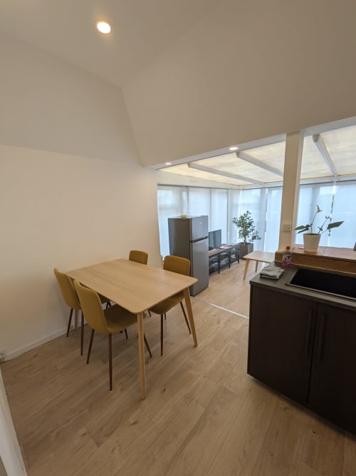 Salle à manger moderne à la Résidence des dunes, Landéda, avec table en bois, chaises jaunes, kitchenette et luminosité