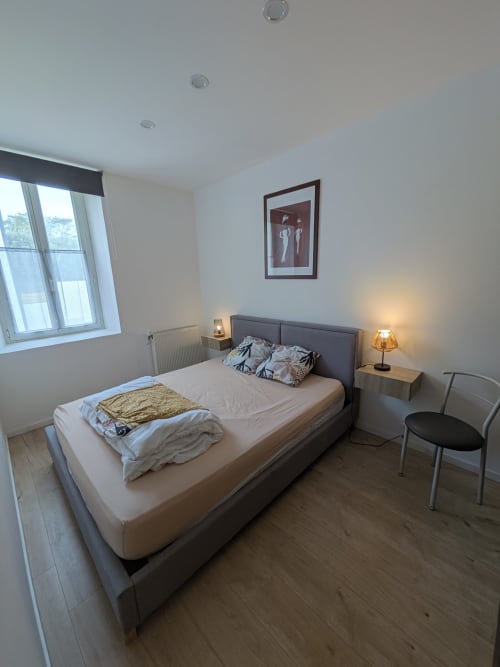 Chambre moderne à la Résidence des dunes à Landéda avec lit queen-size, tables de nuit, lampes, fauteuil, grande fenêtre et tableaux encadrés