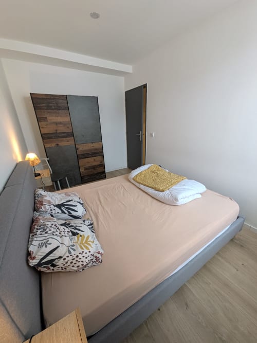 Chambre moderne de l'appartement de Landéda avec lit queen-size, coussins décoratifs, lampe de chevet et armoire miroir à la Résidence des
