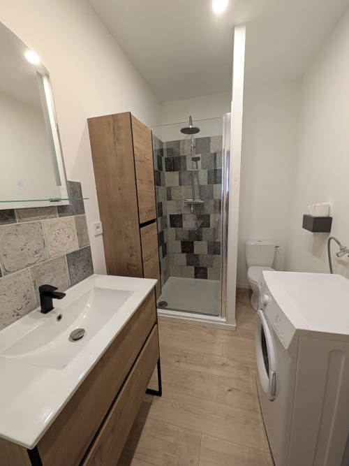 Salle de bain moderne à la Résidence des dunes avec lavabo, douche, toilettes et lave-linge à Landéda