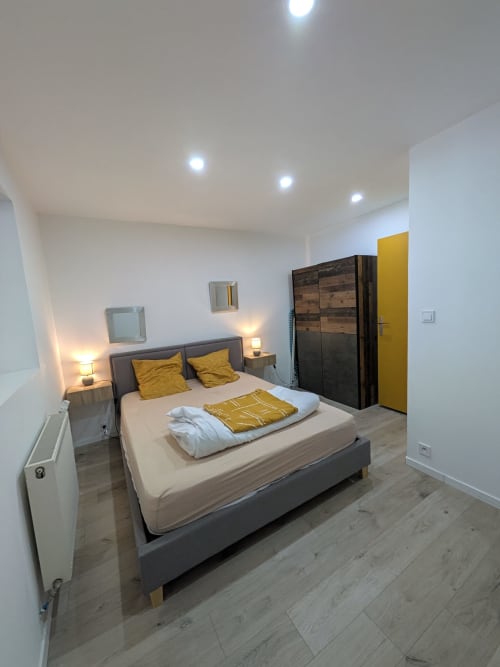 Chambre moderne à la Résidence des dunes à Landéda avec lit gris, accents moutarde, parquet et design contemporain