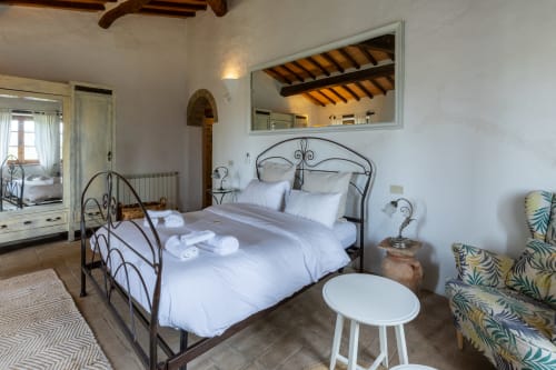 Querce room at Quarantallina hotel in Buonconvento features wrought iron bed with white linens and countryside views