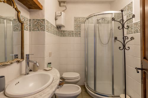Modern bathroom with shower enclosure, round sink, and decorative tile border at Quarantallina hotel in Buonconvento, Italy