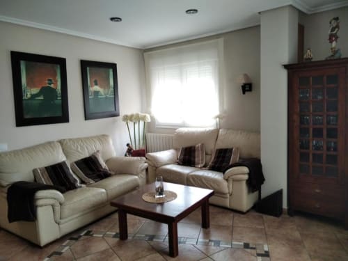 Amplia sala de estar con sofás crema, mesa de café de madera y cuadros enmarcados en Casa Lahuerta 2