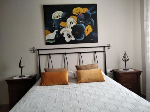 Dormitorio en Casa Lahuerta 2 con cabecero de hierro forjado, colchón blanco, almohadas naranjas, mesillas de madera oscura y detalles florales