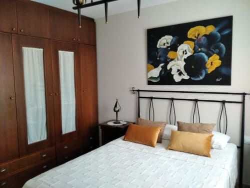 Dormitorio con cama de hierro forjado, almohadas naranjas, armario de madera y cuadros florales en Casa Rural El Abuelo Lahuerta