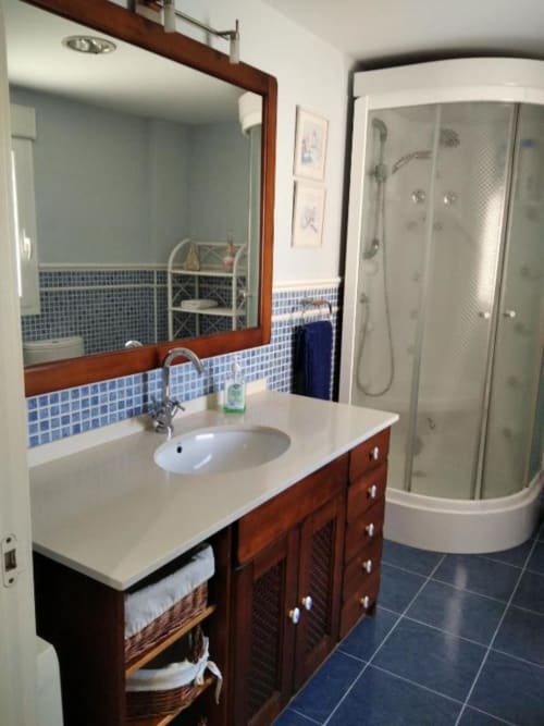 Baño moderno en Casa Lahuerta 2 de Bronchales con mueble de madera, azulejos azules y ducha con cerco curvo