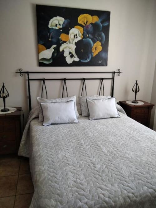 Dormitorio de Casa Lahuerta 2 con cama de hierro forjado, ropa de cama blanca y cuadros florales sobre el cabecero en Bronchales rural