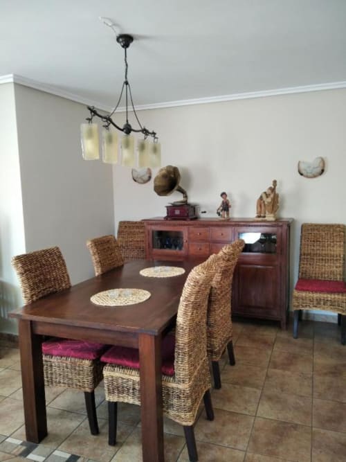 Comedor de Casa Lahuerta 2 con mesa de madera, sillas de mimbre, lámparas colgantes y muebles antiguos en Bronchales