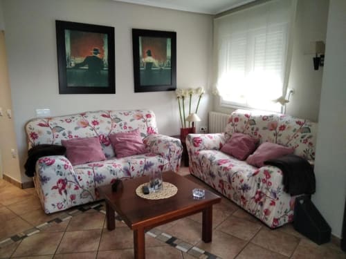 Sofás con estampado floral y cojines rosa en la sala de estar Casa Lahuerta 2 de Casa Rural El Abuelo Lahuerta, Bronchales