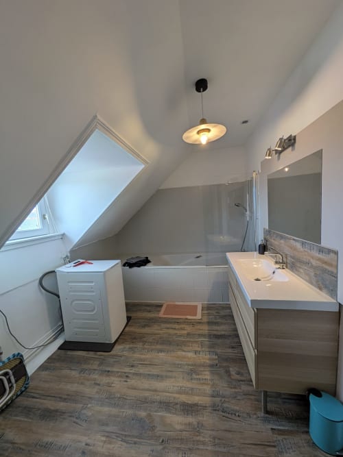 Salle de bain moderne sous les combles à la Résidence des dunes à Landéda avec puits de lumière, vasque, douche et revêtement effet bois