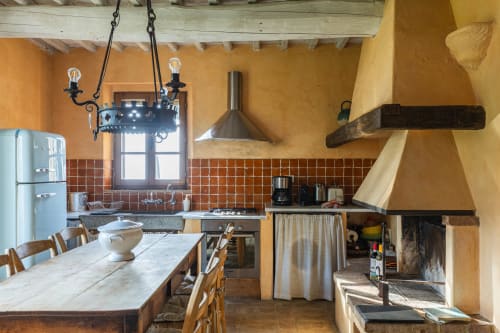 Cucina italiana rustica con pareti gialle, backsplash in piastrelle rosse, elettrodomestici vintage e zona pranzo all'hotel QUARANTALLINA