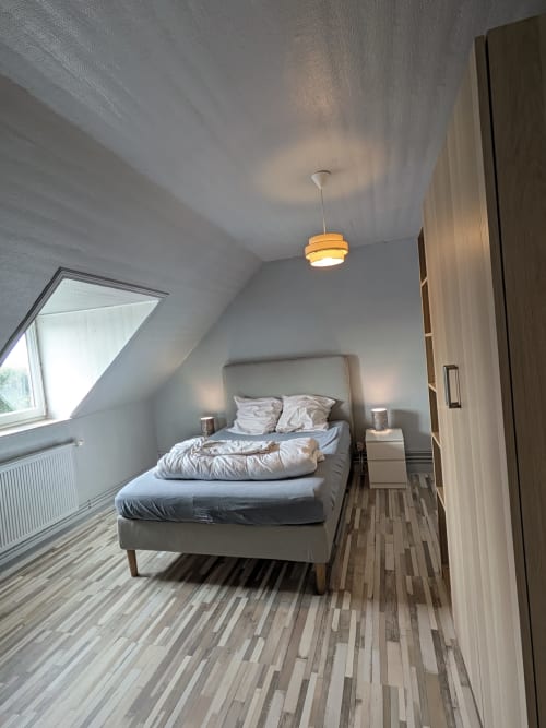 Chambre mansardée moderne à la Résidence des dunes à Landéda avec lit queen-size, suspension et parquet à motifs rayés