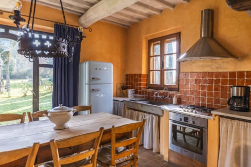 Appartamento in cucina rustica italiana a Buonconvento con muri arancioni, frigorifero vintage, tavolo da pranzo in legno