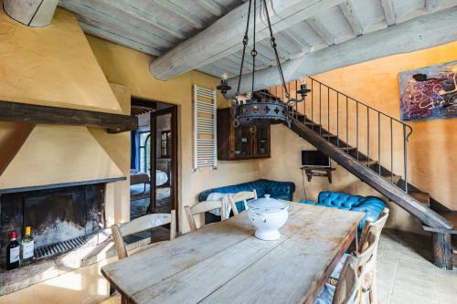 Appartamento rustico italiano con camino, tavolo in legno, sedute con cuscini blu e soffitto con travi a vista