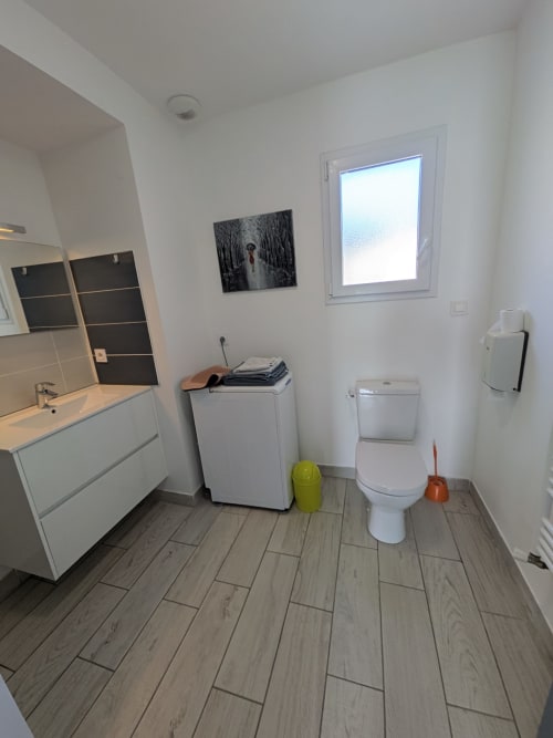 Salle de bains moderne à la Résidence des dunes, Landéda avec vasque blanche, WC, machine à laver et revêtement imitation bois