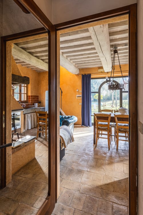 Appartamento rustico italiano a Buonconvento con zona pranzo aperta, muri arancioni, travi a vista e vista sulla campagna