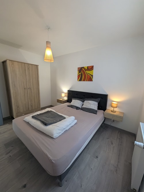 Spacieuse chambre à la Résidence des dunes BnB à Landéda, France avec lit queen-size, armoire en bois, luminaire suspendu et