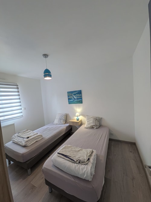 Chambre twin à la Résidence des dunes à Landéda avec deux lits simples, suspension bleue et tableau de voilier