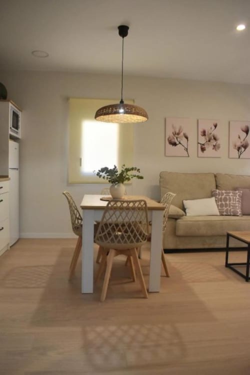 Interior moderno de apartamento con mesa de comedor, lámpara colgante, sofá beige y cocina en Casa Rural El Abuelo, Bronchales