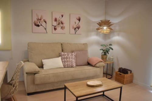 Acogedora sala de estar en el apartamento Casa El Abuelo con sofá beige, mesa de café de madera y cuadros florales rosa en Bronchales