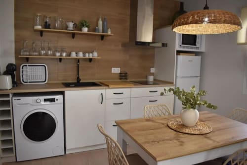 Cocina y comedor modernos de Casa Rural El Abuelo con encimeras de madera, armarios blancos y lámpara colgante tejida