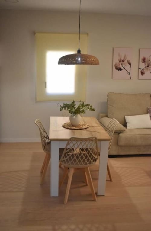 Comedor moderno del apartamento Casa El Abuelo con mesa de madera, sillas tejidas, lámpara colgante y sofá beis en Bronchales