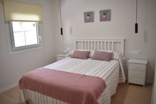 Dormitorio luminoso en Casa El Abuelo, apartamento rural en Bronchales, con cama blanca, detalles rosa y equipamientos modernos
