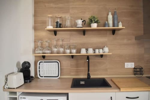 Moderna encimera de cocina con estanterías de madera, fregadero, electrodomésticos y menaje en Casa Rural El Abuelo Lahuerta