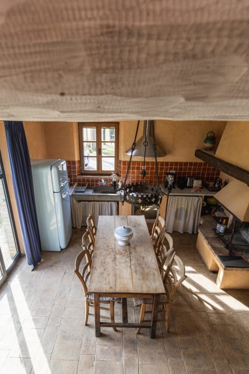 Vista aerea di una rustica sala da pranzo italiana con tavolo in legno, cucina e dettagli in cotto a Buonconvento