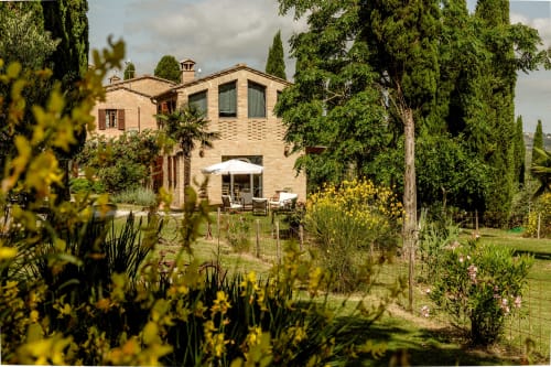 Villa in laterizio toscano con cipressi e giardino fiorito nel cortile di Buonconvento, Italia