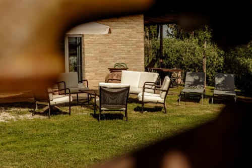 Zona esterna con comode sedie a sdraio presso l'hotel Buonconvento, accanto a edificio in mattoni e giardino.