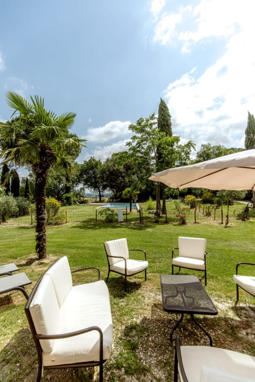 Area lounge della campagna toscana con sedute confortevoli, palma e vista sulla piscina dell'hotel italiano