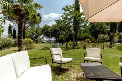 Area lounge esterna dell'hotel Quarantallina a Buonconvento con lettini, ombrellone e giardini curati