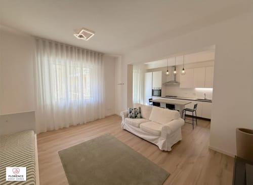 Moderno appartamento Ferrucci a Firenze con zona living open-plan, cucina, divano color crema, pavimenti in legno e vista sul giardino