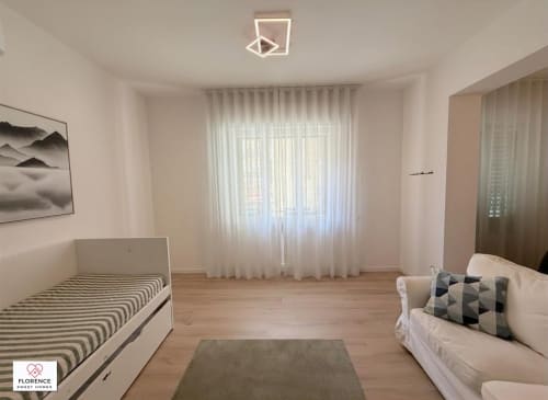 Camera da letto luminosa a Florence Sweet Homes con due letti, tende trasparenti, pavimenti in legno e vista sul giardino