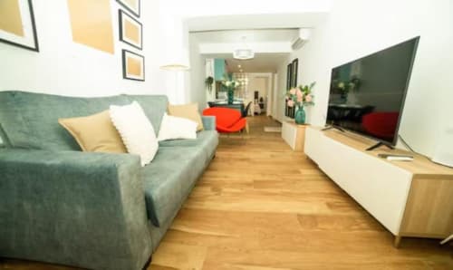 Moderno apartamento Las Arenas en Valencia con sofá verde, suelos de madera, TV y mobiliario contemporáneo