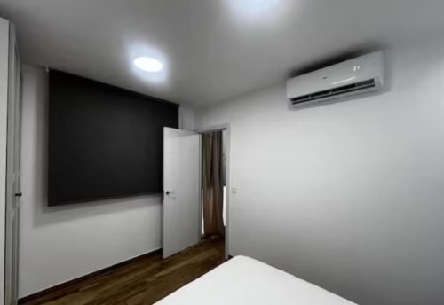 Dormitorio del apartamento Las Arenas con TV de pared, aire acondicionado, suelos de madera y mobiliario moderno en València
