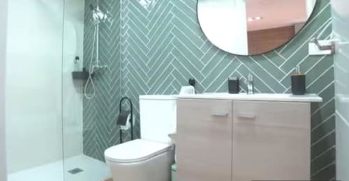 Baño moderno en apartamento Las Arenas, Valencia con azulejos de espiga, lavabo blanco, inodoro y ducha abierta