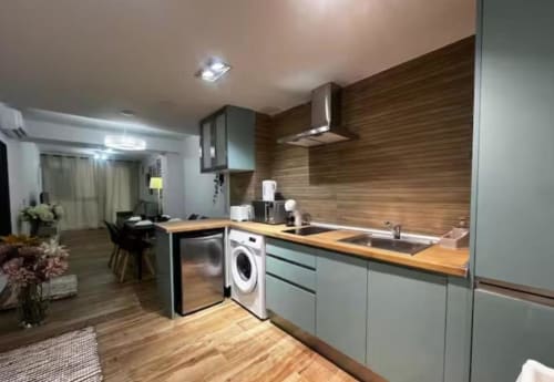 Cocina moderna en apartamento de Las Arenas, Valencia con detalles en madera, electrodomésticos de acero inoxidable y sala abierta