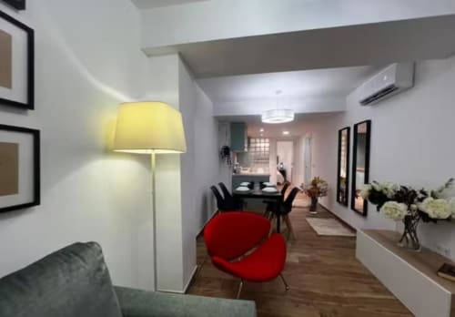 Sala de estar del apartamento Las Arenas en Valencia con sillas rojas, lámpara amarilla y mobiliario moderno