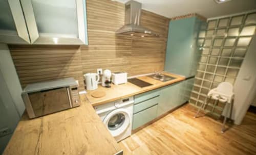 Cocina moderna del apartamento Las Arenas, Valencia con muebles menta, encimeras de madera y electrodomésticos de acero inoxidable