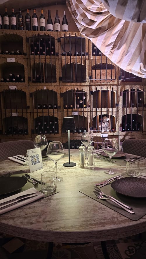 Table de gastronomie à l'hôtel Ô Château de Hayange avec verres à vin et mur de rangement de bouchons