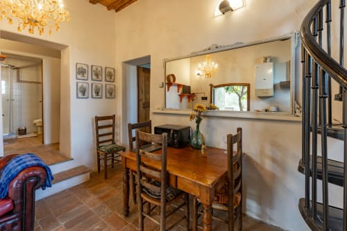 Sala da pranzo rustica toscana dell'hotel Quarantallina con tavolo in legno, pavimenti in terracotta e vista della cucina